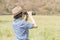 Woman wear hat and hold binocular in grass field