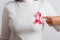 Woman wear white shirt pointing finger to pink breast cancer awareness ribbon