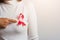 Woman wear white shirt pointing finger to pink breast cancer awareness ribbon