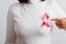 Woman wear white shirt pointing finger to pink breast cancer awareness ribbon