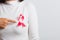 Woman wear white shirt pointing finger to pink breast cancer awareness ribbon