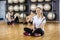 Woman Wearing Activity Tracker While Sitting On Floor In Gym