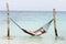 Woman Wearing Bikini And Sun Hat Relaxing In Beach Hammock