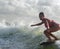 Woman wearing bikini wakesurfing over splashing wave