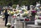 Woman wearing black at the cemetery full of flowers and candels