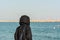 A woman wearing black hijab looking at the sea at the corniche park in Dammam, Kingdom of Saudi Arabia