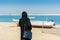 A woman wearing black hijab and a luxury bag looking at the sea at the corniche park in Dammam, Kingdom of Saudi Arabia