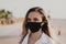 Woman wearing black protective face mask outdoors during summer season