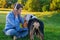 Woman wearing blue coat, black top and jeans listens to music / audiobook and rest on meadow / green grass on sunny spring warm da