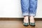 Woman wearing blue jeans and green shoes, standing and waiting in the office.Shot of plus size woman legs, feshion concept