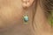 Woman wearing brass metal earring with mineral gemstone