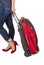 Woman Wearing Capri Blue Jeans and Suede Red Pumps Pulling a Small Travel Luggage