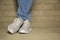 Woman wearing casual clothing and white sneakers leaning wall in city