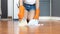 Woman wearing cleaning gloves uses a broom to collect paper scraps from the floor of the room