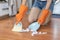 Woman wearing cleaning gloves uses a broom to collect paper scraps from the floor of the room