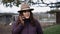 Woman wearing a cowboy hat talking on the phone on a farm