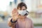 Woman wearing disposable medical mask showing gesture Stop - keep social distance while coronavirus epidemic. Stay at home during