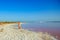 Woman wearing elegant summer dotted dress walking at bang of salty pink lake with crystals of salt. Extremely salty pink lake,