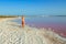 Woman wearing elegant summer dotted dress walking at bang of salty pink lake with crystals of salt. Extremely salty pink lake,