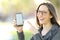 Woman wearing eyeglasses showing a phone screen