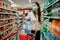 Woman wearing face mask buying bottled water in supermarket/drugstore with sold-out supplies.Prepper buying bulk supplies due to