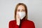 Woman wearing a face mask, close up, isolated on grey background. Flu epidemic, dust allergy,  protection against virus,