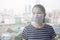 Woman wearing face mask of N95 because of air pollution in the city have particulate matters or PM 2.5 with city building.