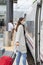 Woman wearing a face mask and pulling suitcases about to enter a train at a train station. Travel and safety concept