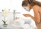 Woman wearing facial cosmetic mask washing face