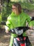 Woman wearing green raincoat on scooter moped.