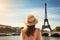 A woman wearing a hat poses in front of the iconic Eiffel Tower in Paris, tourist woman in summer dress and hat standing on