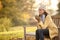 Woman Wearing Hat And Scarf With Hot Drink Sitting On Bench On Walk In Autumn Countryside