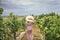 Woman, wearing a hat, in a vineyard in the sun