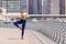 Woman wearing headphones stands in the hatha yoga tree pose after a running workout in the Dubai Marina Embankment