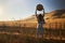 Woman wearing jeans and flannel from behind looking at view of rural california landscape holding up hat in air