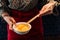 Woman wearing kimono is beating hen egg with chopsticks for dipping with sukiyaki beef