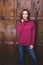 Woman wearing magenta sweatshirt in front of wooden wall