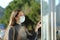 Woman wearing a mask checking schedule in a bus stop