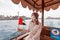 Woman wearing a medical mask with the flag of the UAE is traveling on the traditional boat ferry Abra Dhow on the Dubai