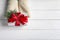 Woman wearing mittens holding Christmas gift on wooden background