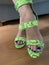 Woman wearing neon snakeskin shoes with blue nail polish