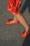 Woman wearing orange dress and bright orange shoes.