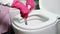 Woman wearing pink gloves cleaning toilet bowl