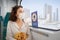 Woman wearing a protective face mask sits on a subway seat and looks hopefully out the window with Dubai views. The concept