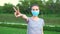 Woman wearing protective mask in the park and show peace gesture.