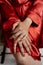 a woman wearing red and holding her right arm on her thigh