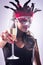 Woman wearing red mask at masquerade party drinking champagne