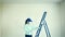 A woman wearing a respirator polishes a wall after applying plaster before painting