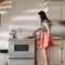 Woman wearing retro dress in kitchen using frying pan  to cook