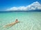 Woman is wearing Santa hat in bikini and swim in water at beach.